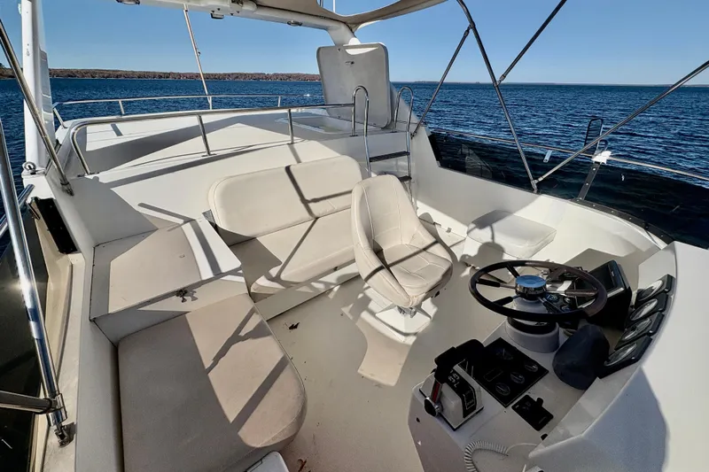 Kronberg Yacht Photos Pics 1990 Neptunus 145 AC yacht cockpit with steering wheel and seating, overlooking calm waters.