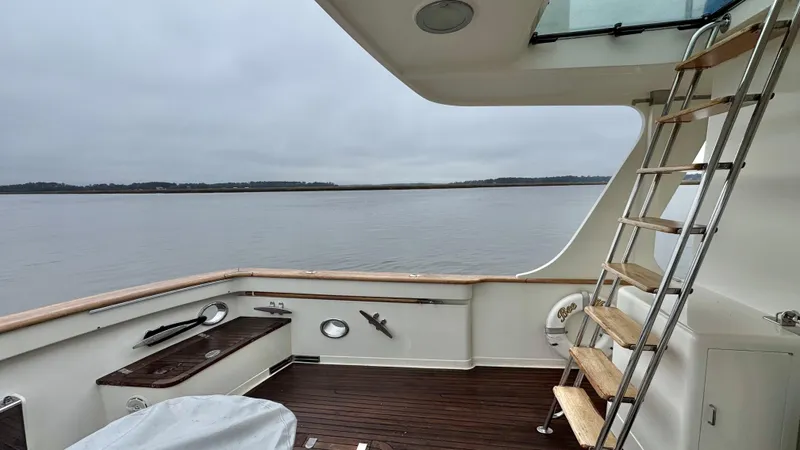 Bee Haven Yacht Photos Pics Fleming 65 Pilothouse Motor Yacht 2006, spacious deck with wooden flooring and ladder, serene waterscape.