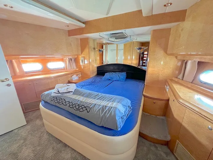 Curiosity Yacht Photos Pics Luxurious bedroom interior of 2001 Elegance 82 S yacht with blue bedding and wood accents.
