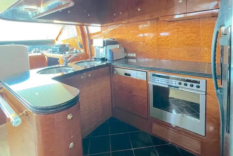 Curiosity Yacht Photos Pics Luxurious yacht kitchen with modern appliances, wood finish, and black countertops in Elegance 82 S, 2001.
