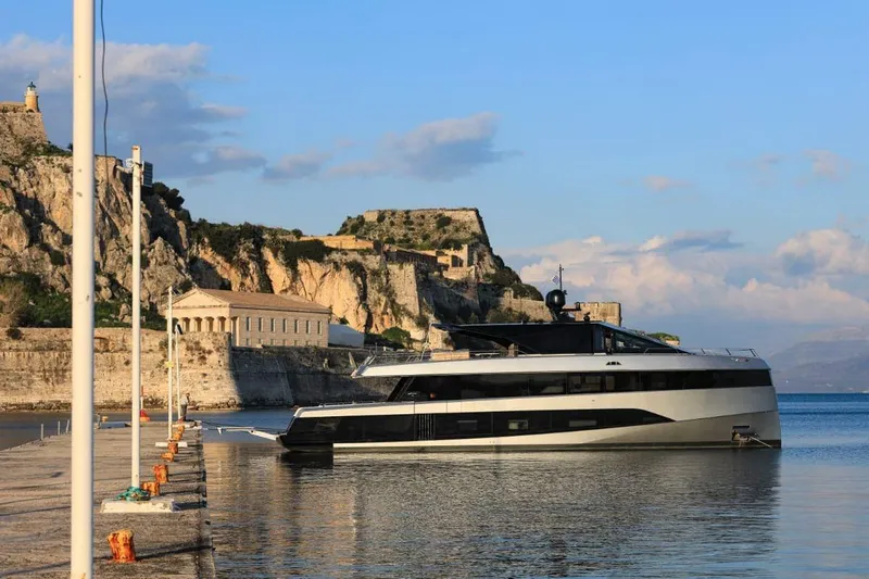 Carat Yacht Photos Pics 2024 WallyWhy200 yacht docked near historic coastal fortress under blue sky.