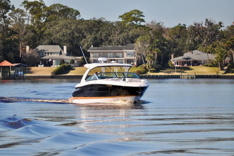  Yacht Photos Pics 2019 Four Winns H350 OB boat cruising on a calm lake near waterfront homes.