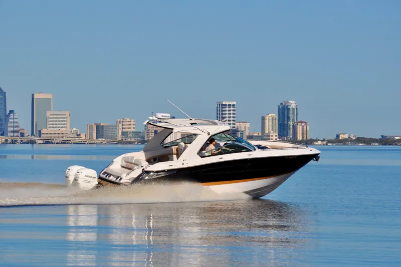  Yacht Photos Pics 2019 Four Winns H350 OB boat cruising on calm water with city skyline backdrop.