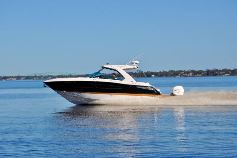  Yacht Photos Pics 2019 Four Winns H350 OB boat cruising on a calm lake under a clear blue sky.