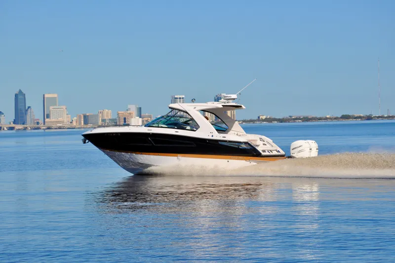  Yacht Photos Pics 2019 Four Winns H350 OB cruising on calm waters with city skyline backdrop.