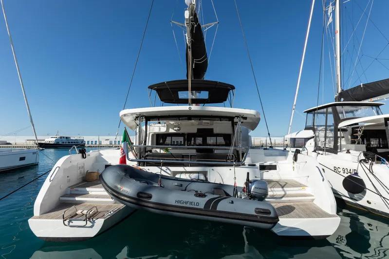 Twenty Cent Yacht Photos Pics 2021 Lagoon 46 catamaran docked with inflatable boat, clear blue sky background.