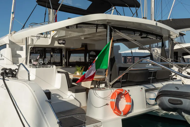 Twenty Cent Yacht Photos Pics 2021 Lagoon 46 yacht with outdoor seating and flag, docked at marina.