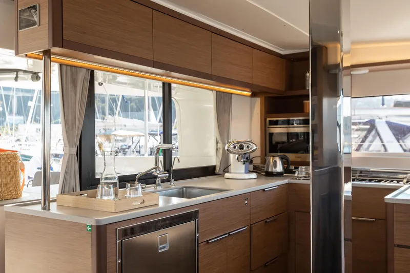 Twenty Cent Yacht Photos Pics Modern kitchen interior of 2021 Lagoon 46 yacht with sleek wood cabinetry and appliances.