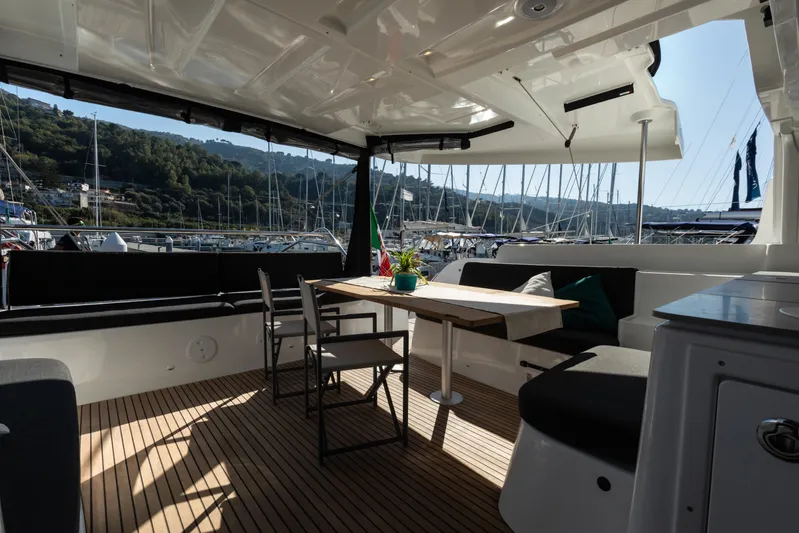 Twenty Cent Yacht Photos Pics Luxurious 2021 Lagoon 46 yacht interior with seating and dining area, docked in a scenic marina.