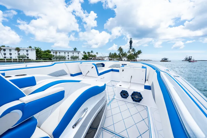  Yacht Photos Pics 2019 Deep Impact 399 Sport boat with blue and white interior, docked near a lighthouse.