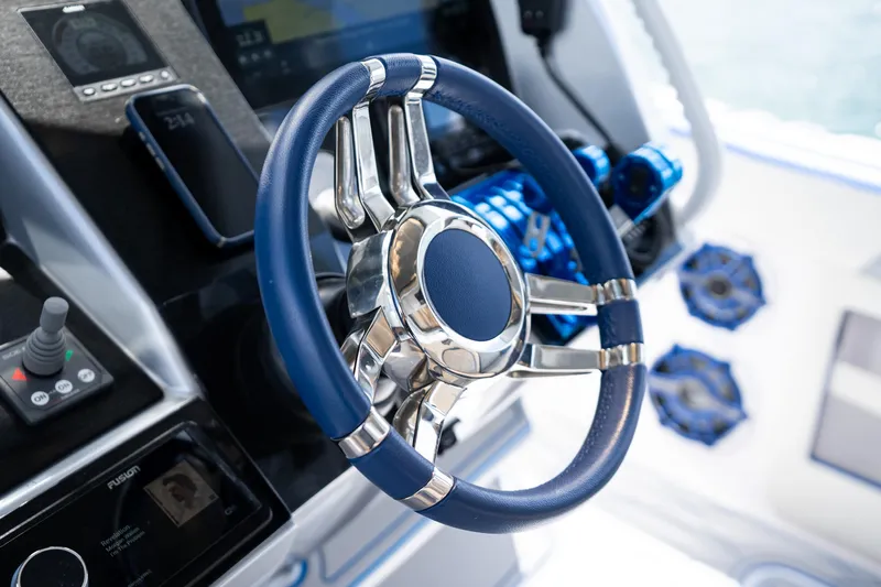  Yacht Photos Pics Steering wheel of 2019 Deep Impact 399 Sport boat, featuring modern controls and blue accents.