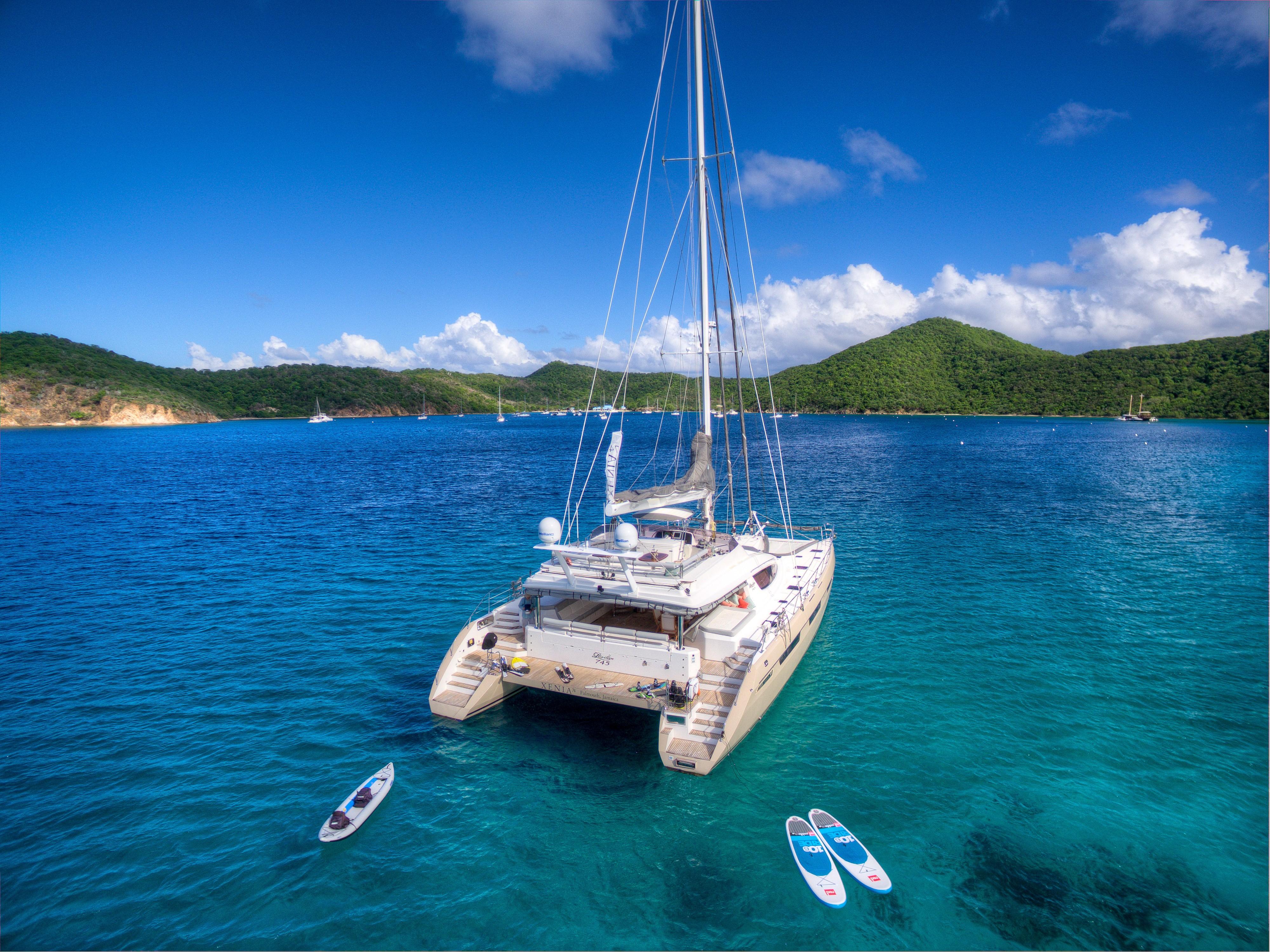 Luxury Privilege 745 yacht anchored in clear blue waters, surrounded by paddleboards, 2010 model.