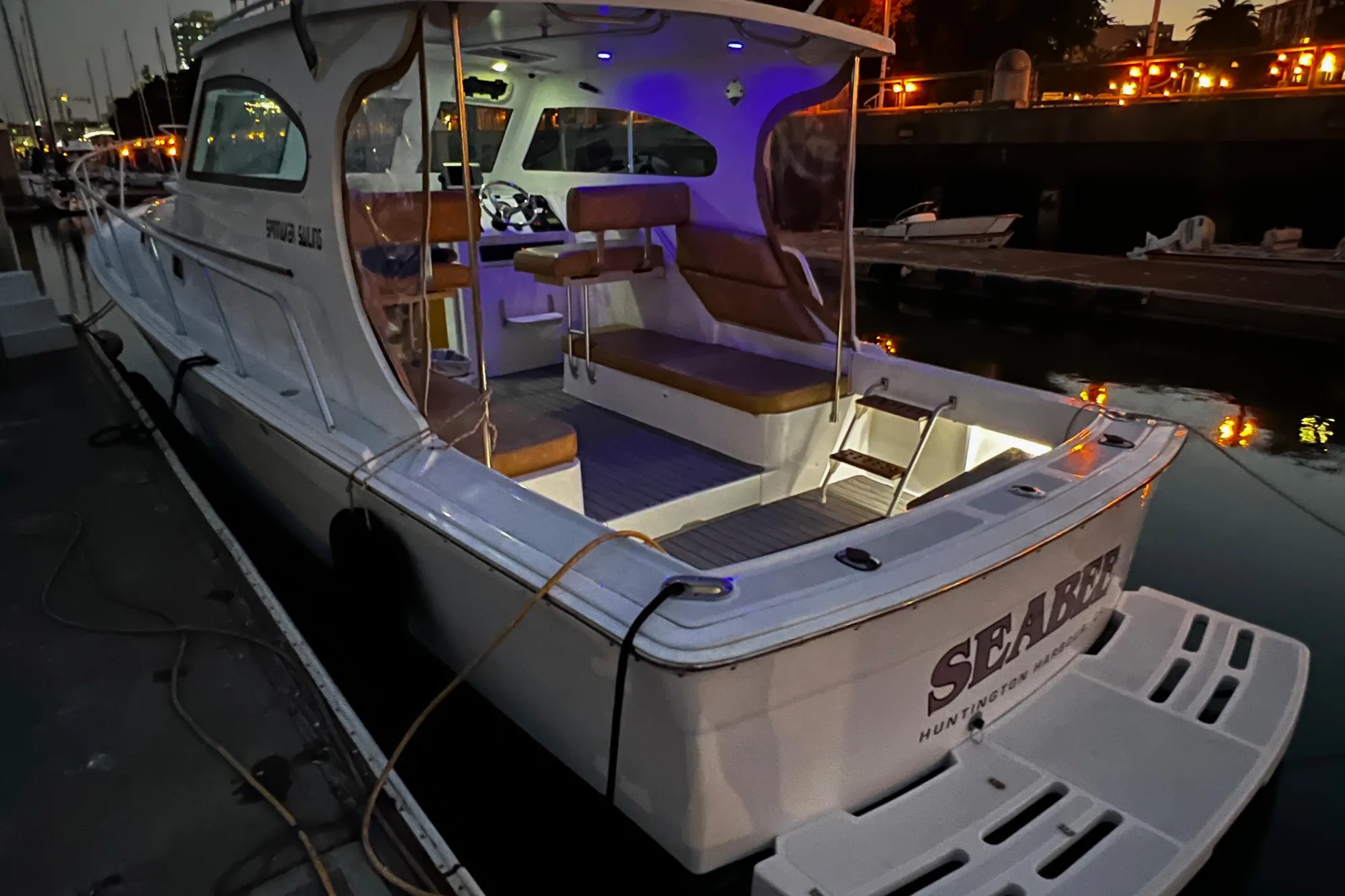1999 Mainship Pilot 30 docked at sunset, featuring illuminated interior and spacious deck.