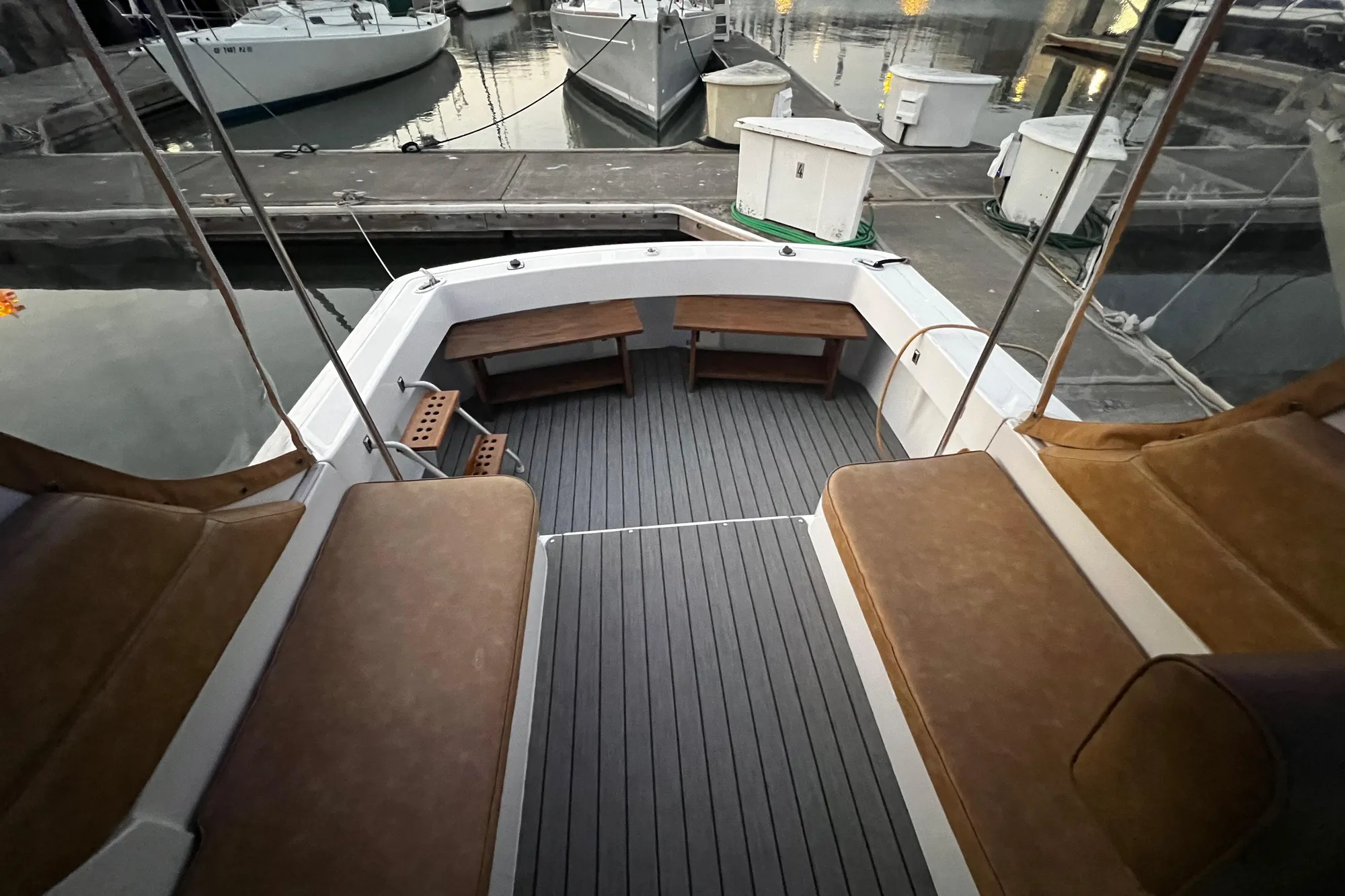 1999 Mainship Pilot 30 boat deck with cushioned seating and wooden flooring at a marina.