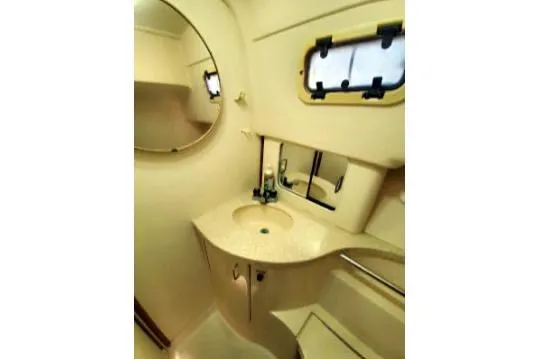 1999 Mainship Pilot 30 boat bathroom with sink, mirror, and porthole window.