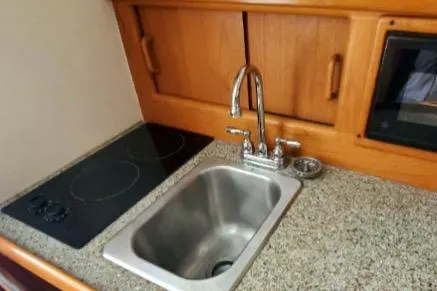 1999 Mainship Pilot 30 galley with sink, stovetop, and wooden cabinetry.
