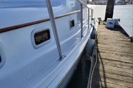 1999 Mainship Pilot 30 docked, showcasing sleek white hull and wooden railings.