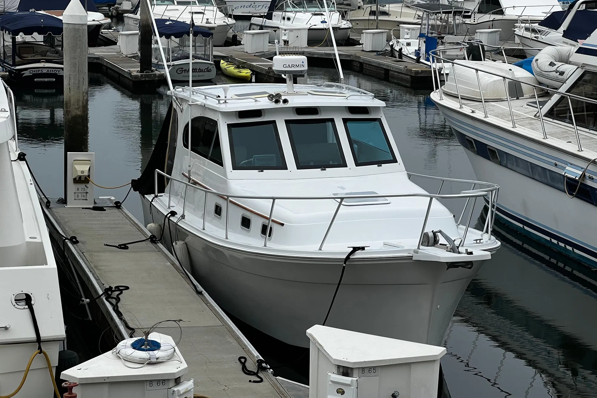 1999 Mainship Pilot 30 docked at a marina, surrounded by other boats.