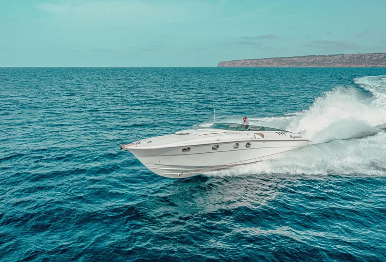 White Chocolate Yacht Photos Pics Magnum 44 yacht cruising on open sea, 2003 model, with scenic coastline in background.