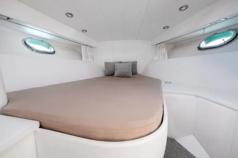 White Chocolate Yacht Photos Pics Luxurious cabin interior of 2003 Magnum 44 yacht with cozy bed and porthole windows.