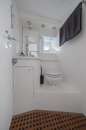 White Chocolate Yacht Photos Pics Compact bathroom in a 2003 Magnum 44 boat with modern fixtures and wooden flooring.