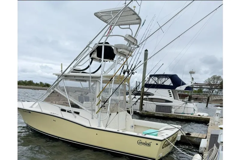  Yacht Photos Pics 2005 Carolina Classic 28 boat docked, equipped with fishing rods and tower, overcast sky.