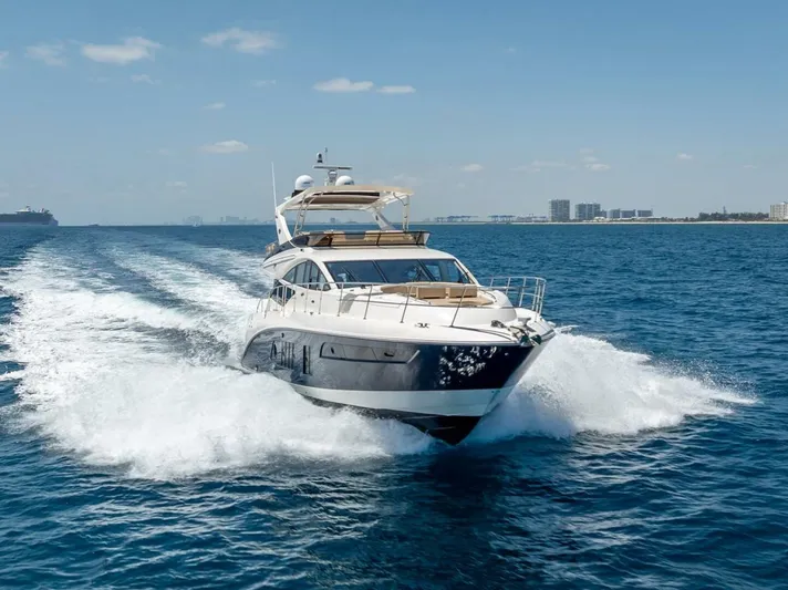  Yacht Photos Pics 2016 Sea Ray L650 Fly yacht cruising on open water, clear sky, city skyline in background.