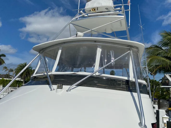 Mad East Yacht Photos Pics 1993 Hatteras 54 Convertible yacht with clear skies and palm trees in the background.