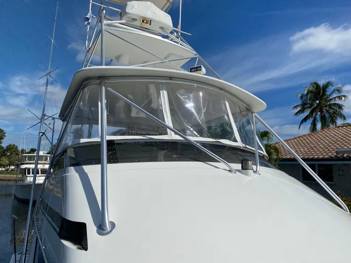 Mad East Yacht Photos Pics 1993 Hatteras 54 Convertible yacht with clear skies and palm trees in the background.