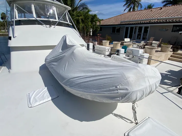 Mad East Yacht Photos Pics 1993 Hatteras 54 Convertible yacht with covered equipment on deck, docked near a house.