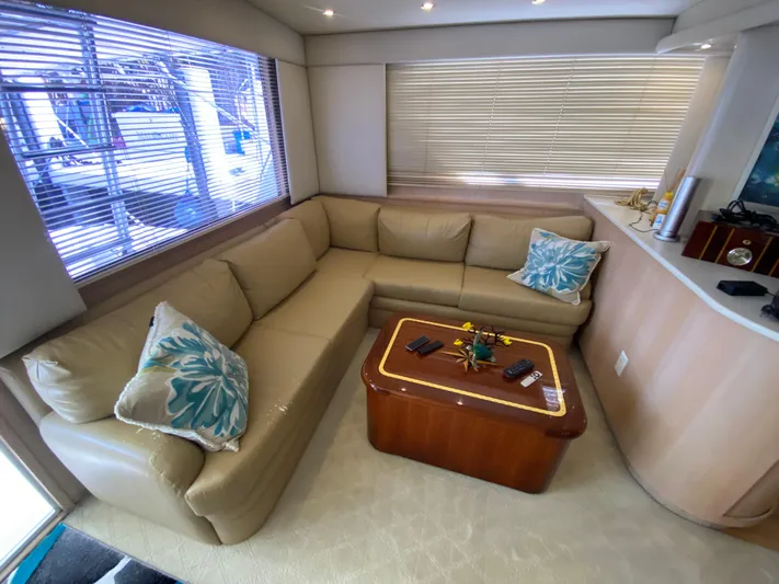 Mad East Yacht Photos Pics Luxurious interior of 1993 Hatteras 54 Convertible yacht with beige leather seating and decorative pillows.