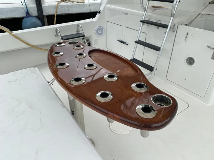 Mad East Yacht Photos Pics 1993 Hatteras Convertible yacht cockpit with polished wood table and rod holders.