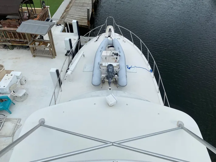 Mad East Yacht Photos Pics 1993 Hatteras Convertible yacht with inflatable boat on deck, docked by the water.