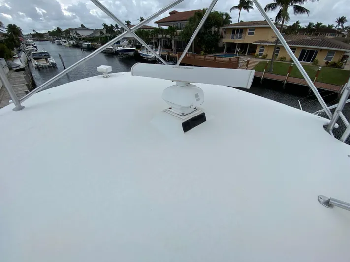Mad East Yacht Photos Pics 1993 Hatteras Convertible yacht deck with radar, docked near waterfront homes.