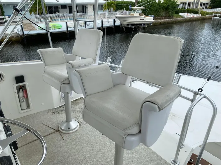 Mad East Yacht Photos Pics 1993 Hatteras Convertible boat with white captain chairs on deck by the water.