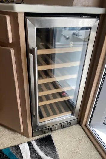 Mad East Yacht Photos Pics Built-in wine cooler with glass door and wooden shelves on a 1993 Hatteras Convertible.