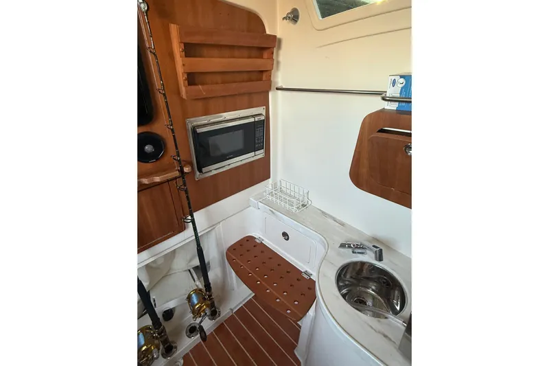 376-420 Brokerage Tyler Yacht Photos Pics 2020 Grady-White Canyon 376 interior with kitchenette, microwave, and fishing rods.