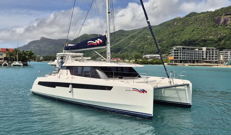 Takamaka Yacht Photos Pics 2020 Leopard 50 catamaran sailing in tropical waters with lush green mountains in the background.