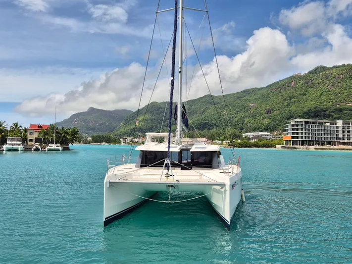 Takamaka Yacht Photos Pics Leopard 50 catamaran sailing in turquoise waters with scenic mountain backdrop, 2020 model.