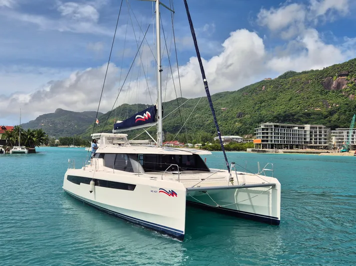 Takamaka Yacht Photos Pics Leopard 50 catamaran sailing in turquoise waters, 2020 model, with scenic mountain backdrop.
