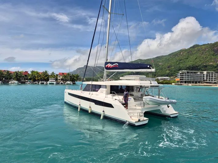 Takamaka Yacht Photos Pics Leopard 50 catamaran sailing in tropical waters, 2020 model, with scenic coastal backdrop.