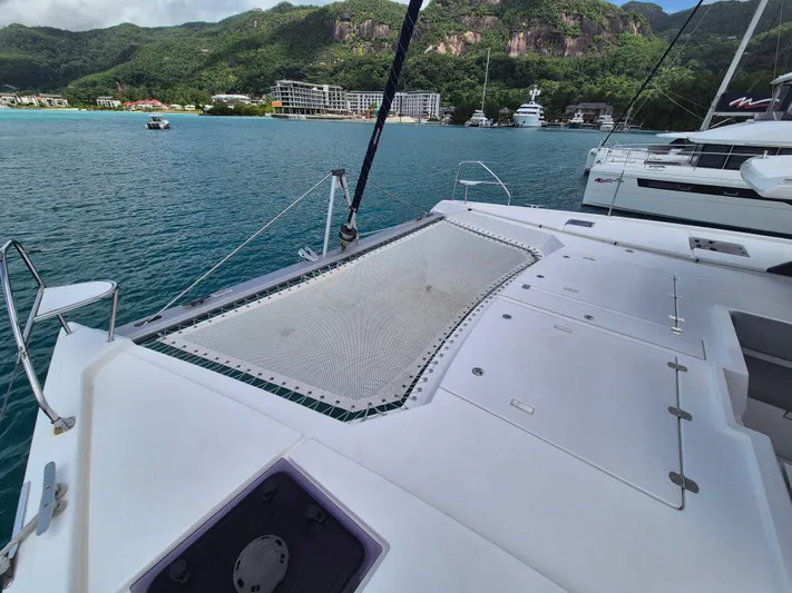 Takamaka Yacht Photos Pics Catamaran deck with netting, Leopard 50, 2020 model, anchored near lush coastal landscape.