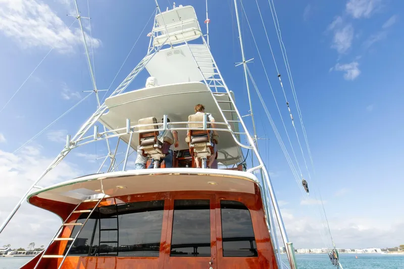 Patron Yacht Photos Pics Custom Ebony Sportfish 65' CNV yacht, 2004 model, with people on deck, under clear blue sky.