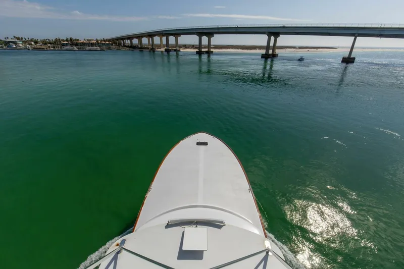 Patron Yacht Photos Pics Bow view of 2004 Custom Ebony Sportfish 65' CNV approaching a bridge over calm green waters.