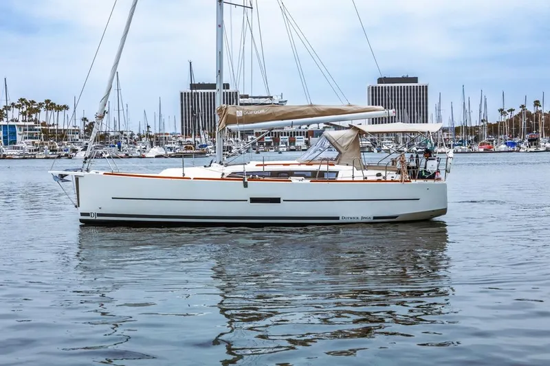 Dotwick Jinga Yacht Photos Pics 2020 Dufour 360 sailboat docked in marina, calm waters, urban skyline background.