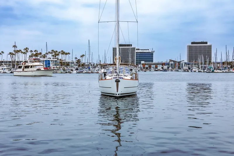 Dotwick Jinga Yacht Photos Pics 2020 Dufour 360 sailboat in a marina with cityscape and palm trees.