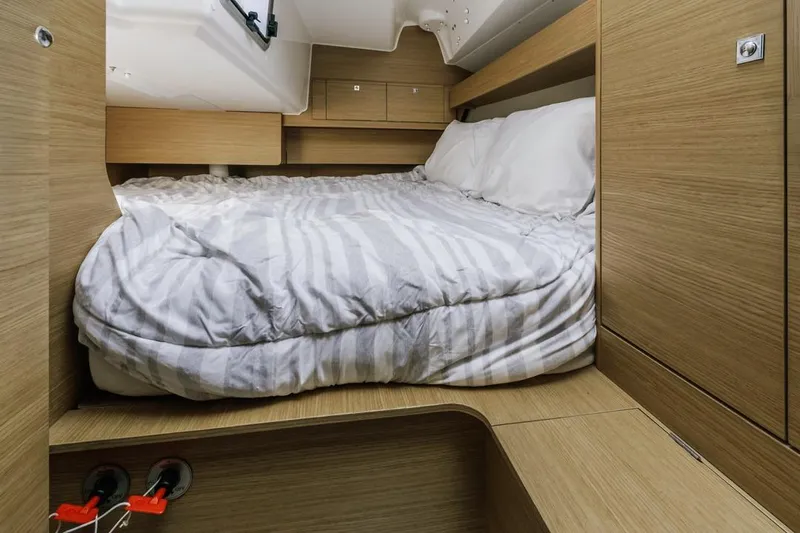 Dotwick Jinga Yacht Photos Pics Cozy cabin interior of 2020 Dufour 360 yacht with striped bedding and wooden finish.