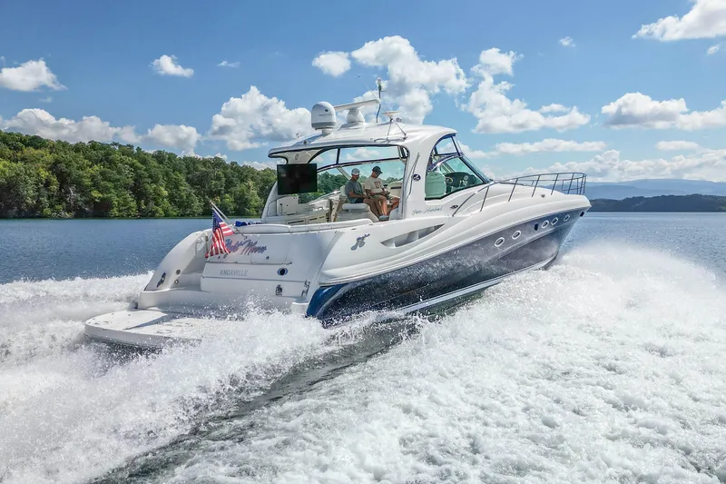 Night Moves Yacht Photos Pics 2005 Sea Ray 500 Sundancer yacht cruising on a scenic lake under a clear blue sky.