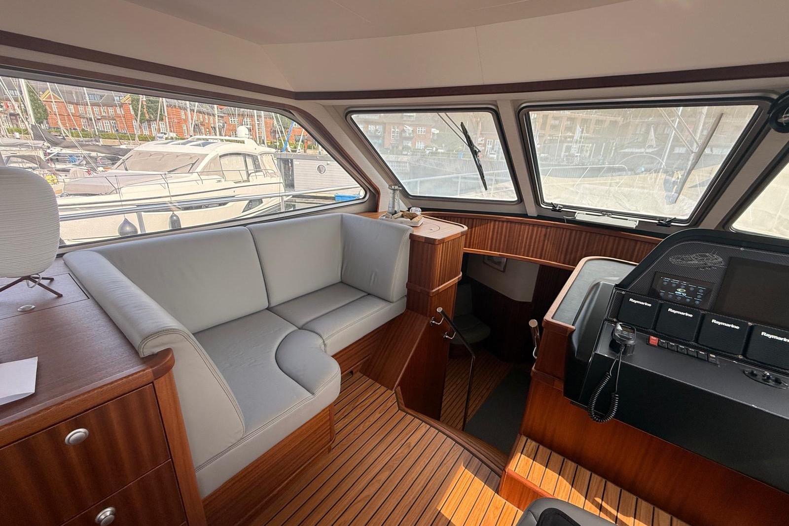 Interior of 2023 Elling E6 yacht with seating and control panel, docked at marina.