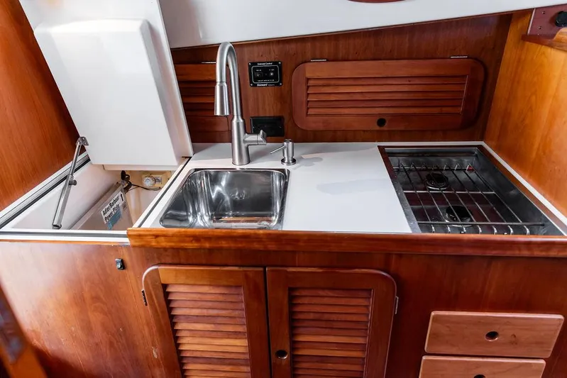 Belle Yacht Photos Pics 1998 Hinckley Picnic Boat galley with sink, stove, and wooden cabinetry.